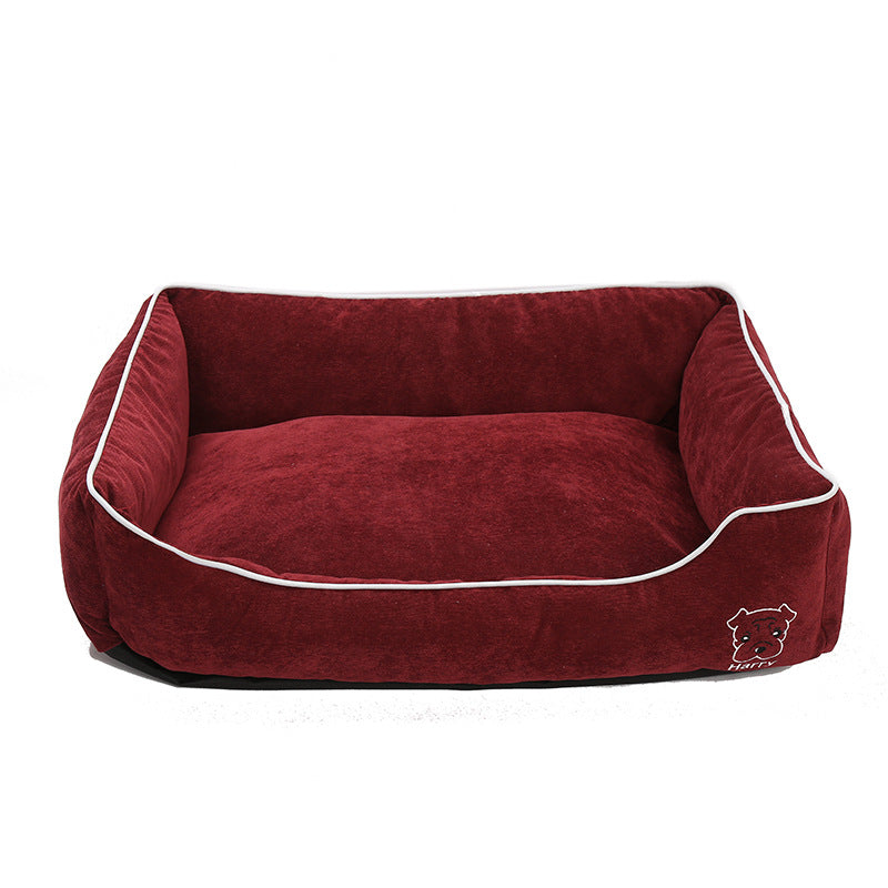 Burgundy corduroy dog bed with white trim and small dog face embroidery on front