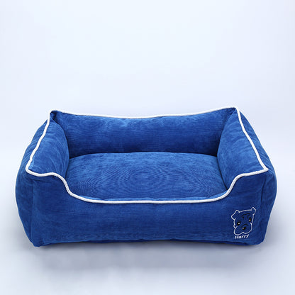 Blue corduroy dog bed with white piping and embroidered dog face labeled Harry on front