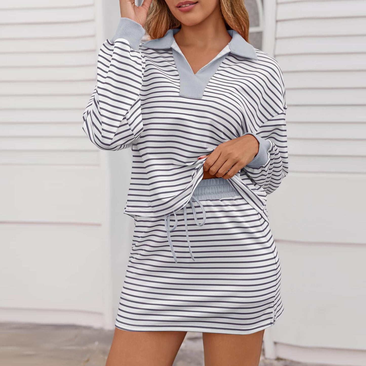 Woman wearing casual white and black striped long sleeve polo top with matching skirt set