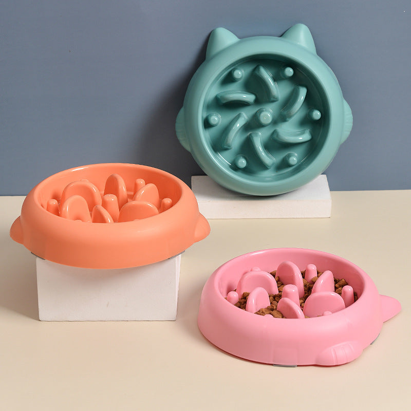 Three colorful slow feeder dog bowls in green, orange, and pink with bone-shaped design and raised obstructions