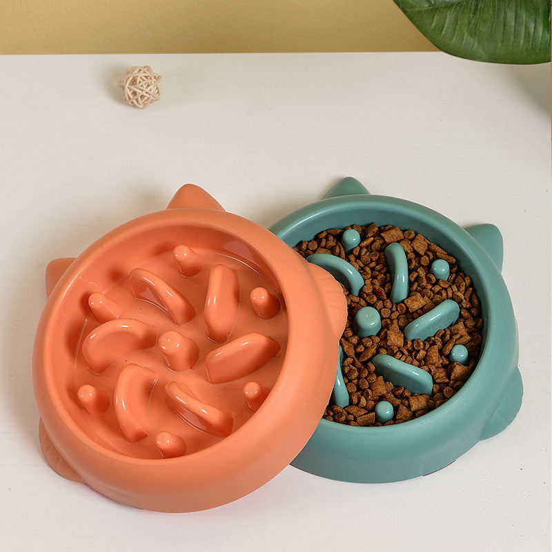 Two bone-shaped slow feeder dog bowls in orange and teal, one filled with dry dog food