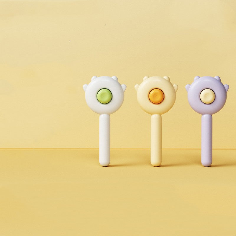 Three pastel-colored pet grooming brushes with circular buttons on yellow background