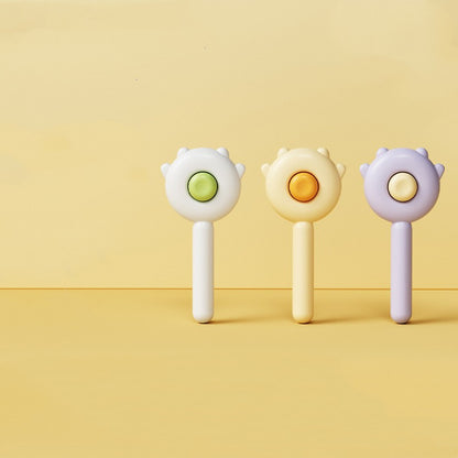 Three pastel-colored pet grooming brushes with circular buttons on yellow background