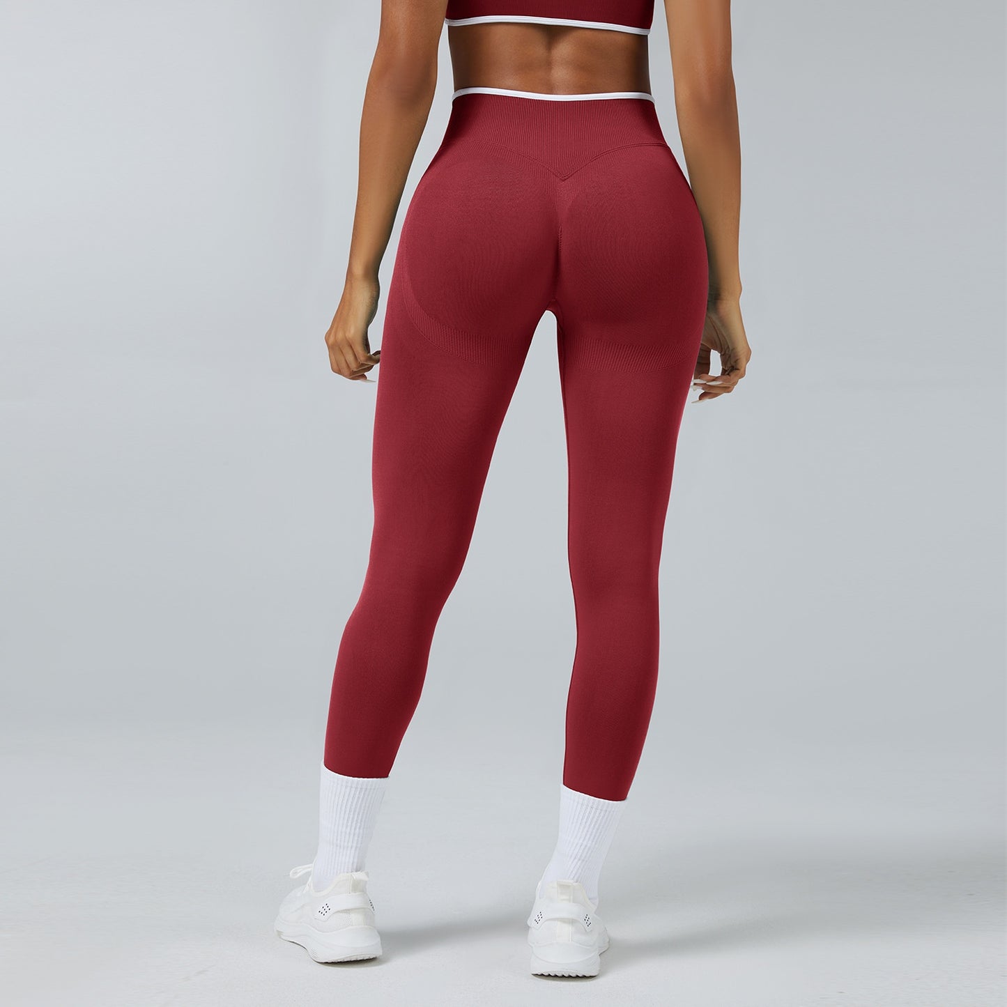 Back view of woman wearing seamless high waist deep red workout leggings with white sneakers and socks