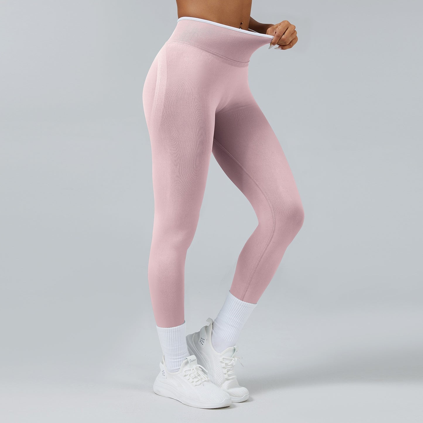 Woman wearing light pink high-waist seamless yoga leggings with white socks and white sneakers