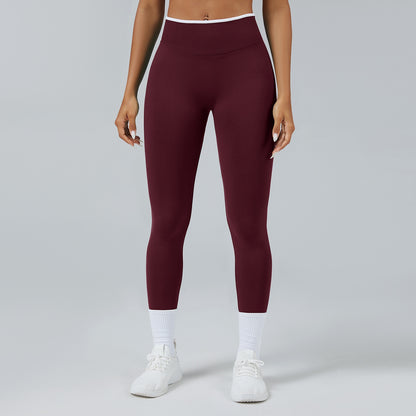 Woman wearing high-waist seamless maroon leggings with white sneakers and socks on gray background