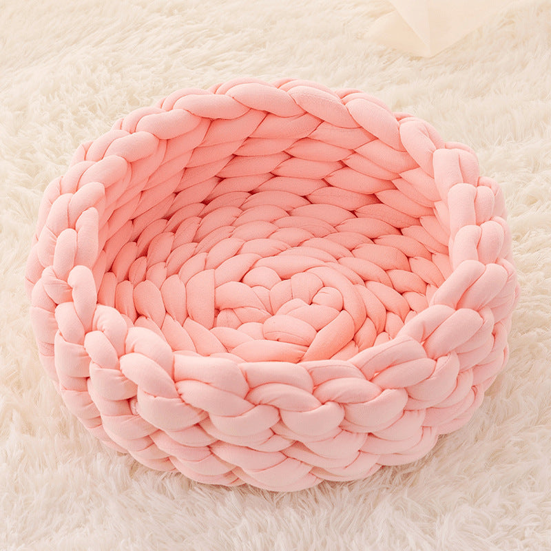 Pink chunky knit soft round plush cat bed on white fluffy rug