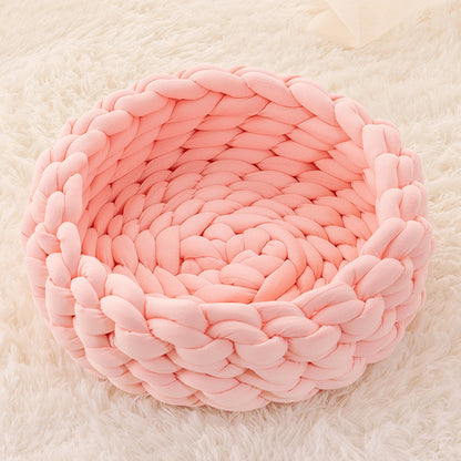 Pink chunky knit soft round plush cat bed on white fluffy rug