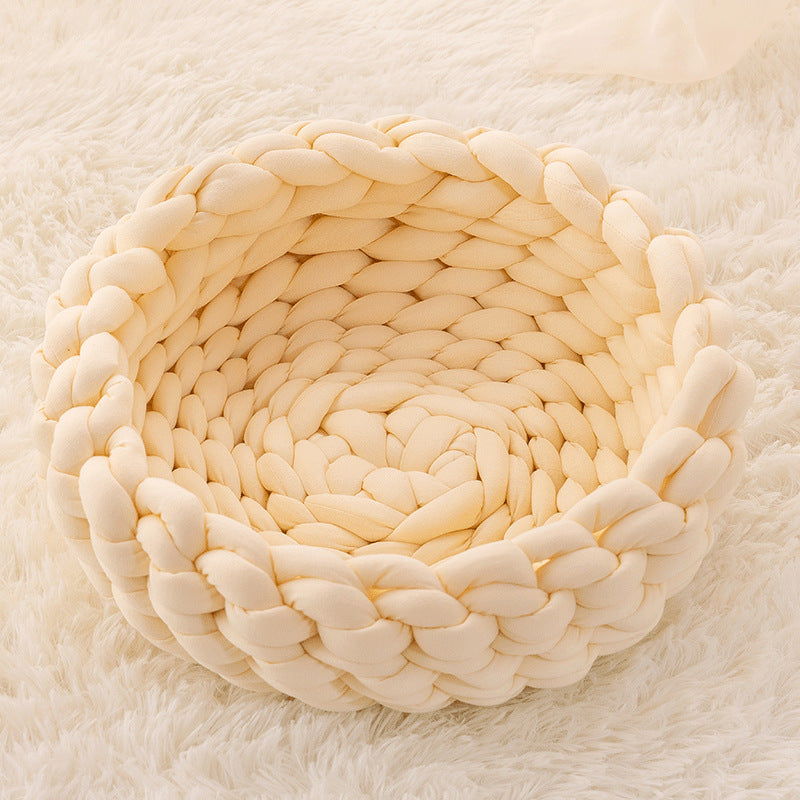 Soft cream-colored chunky knit round pet bed on fluffy white carpet