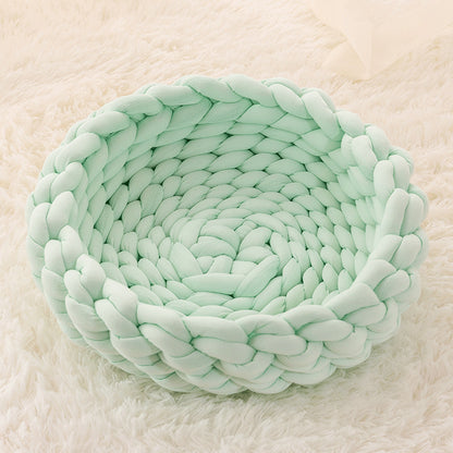 Light mint green cozy braided plush cat bed on a soft cream shag rug
