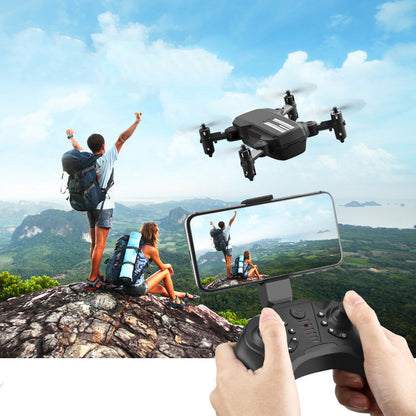 Mini folding drone flying over hikers on mountain with remote controller and live smartphone view