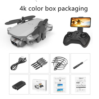 Grey folding mini drone with camera, remote control with phone holder, USB cable, spare propellers, prop guards, screwdriver, battery, and user manuals