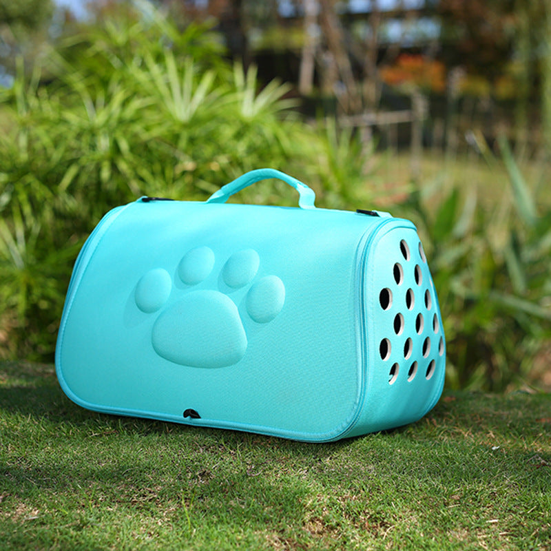 Light blue foldable pet carrier with paw print design and ventilation holes on grass
