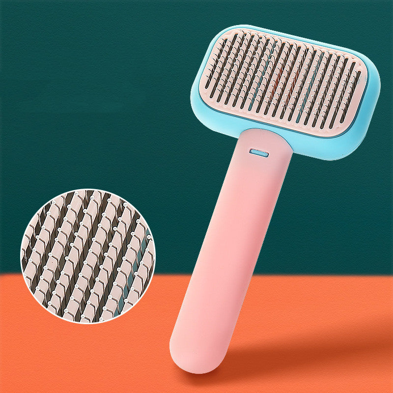 Pink and blue ergonomic pet grooming brush with detailed close-up of flexible metal bristles on orange surface