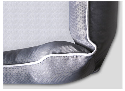 Close-up of dark grey dog bed corner with hexagonal pattern and white piping on removable cover