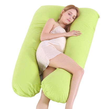 Woman sleeping on a large U-shaped green maternity pillow for pregnancy support