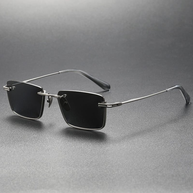 Black and gray rimless rectangular polarized sunglasses with silver metal frame on gray surface