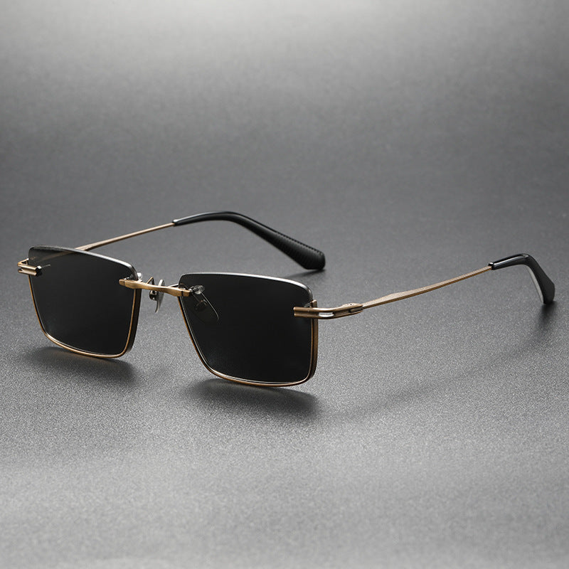 Black and gold rimless square polarized sunglasses on gray surface with retro style