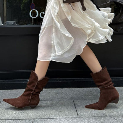 Brown suede pointed toe western boots worn with flowing white skirt walking on pavement