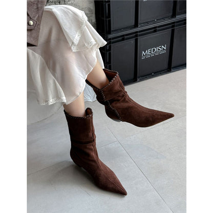 Brown suede pointed toe western boots with stitched edges worn with a white skirt