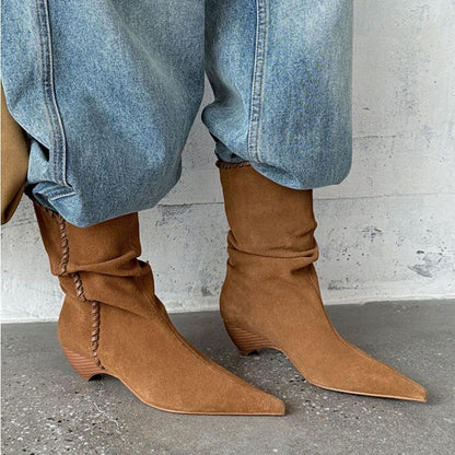 Brown suede pointed toe western boots with low stacked heels worn with light blue denim jeans
