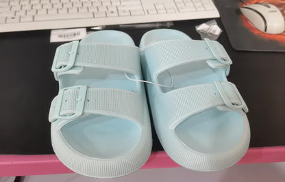 Light blue thick-soled EVA sandals with adjustable straps on a black desk in front of a keyboard