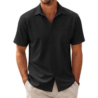 Man wearing black short sleeve button-up casual shirt with chest pocket, paired with light beige pants