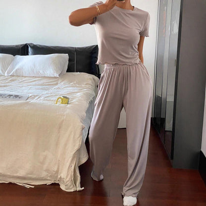 Woman wearing casual light mauve two-piece set with short sleeve top and wide pants in bedroom