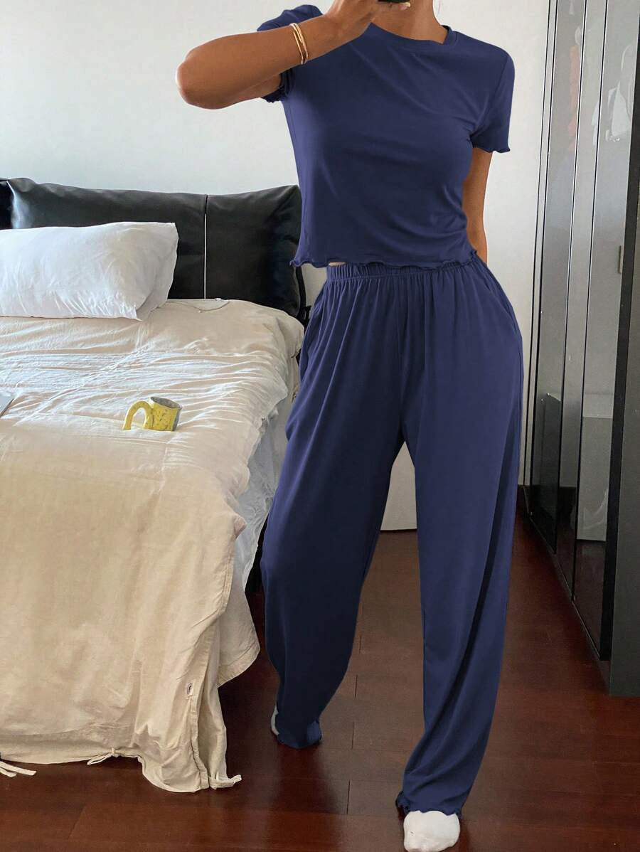 Woman wearing navy blue casual lounge set with short sleeve top and loose pants in bedroom