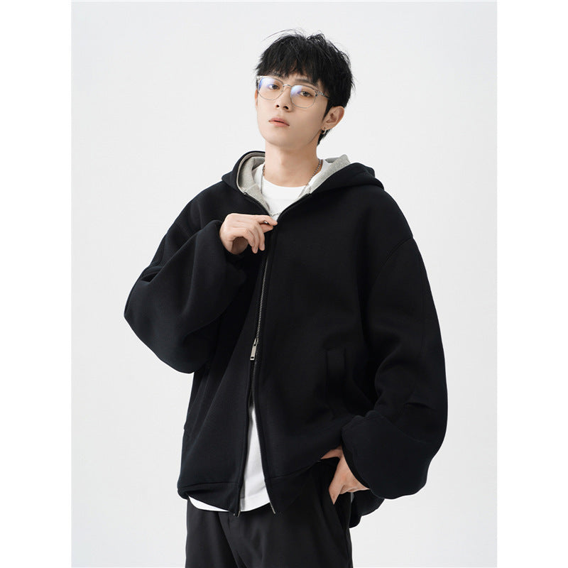 young man wearing black oversized hooded jacket with front zipper and white inner layer against white background