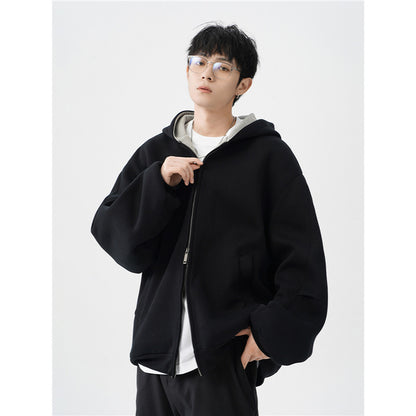 young man wearing black oversized hooded jacket with front zipper and white inner layer against white background