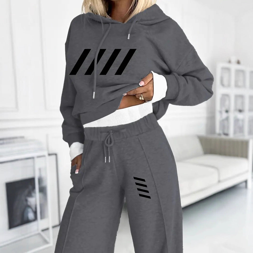 Woman wearing light gray casual hooded sweatshirt and matching sweatpants with black stripe design in modern living room