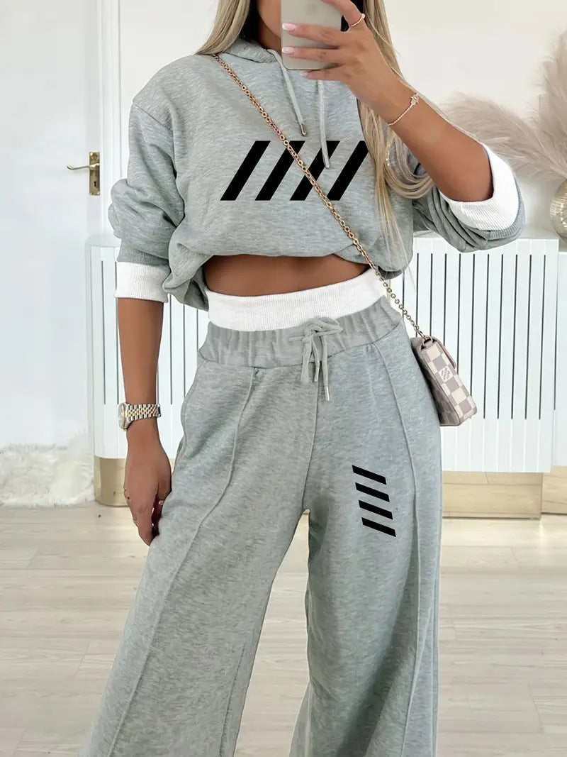 Woman wearing light gray casual hooded sweatshirt and matching wide-leg sweatpants with black stripe design