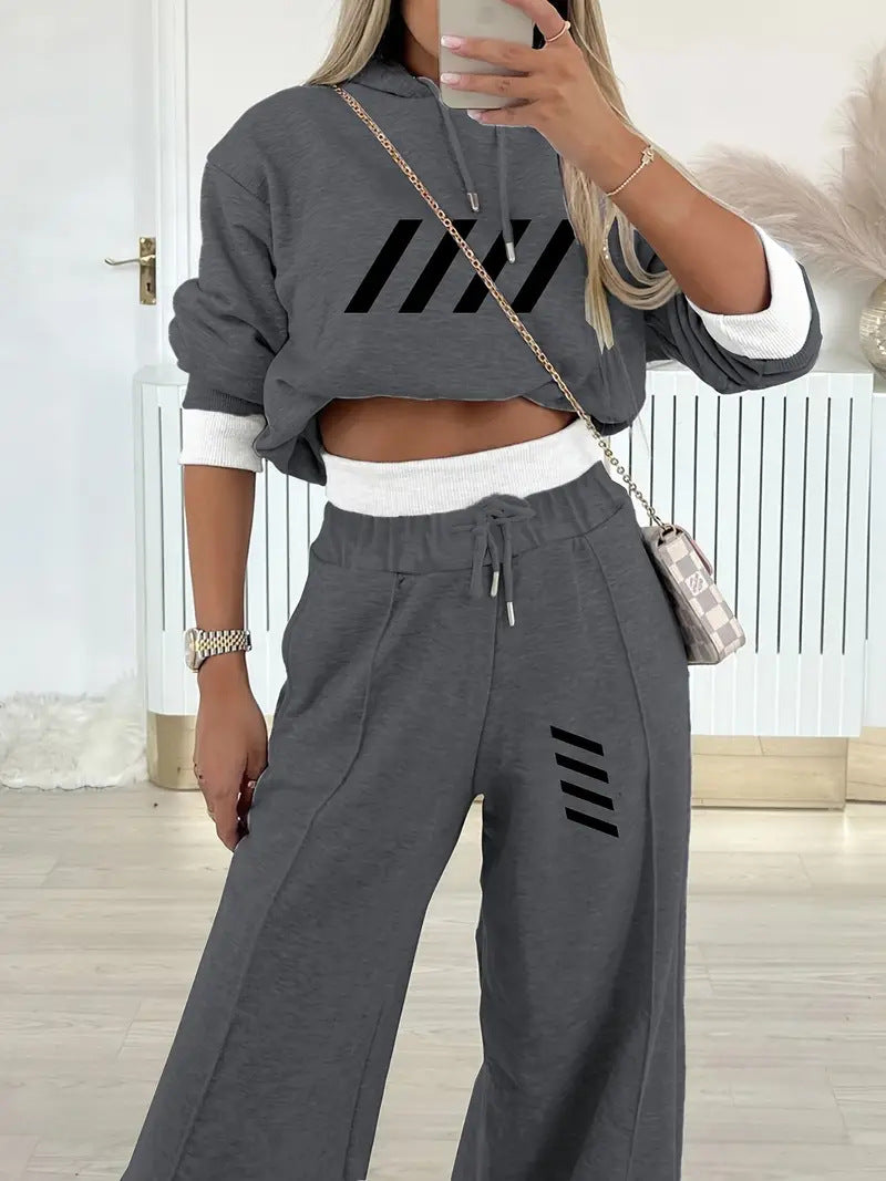 Woman wearing gray two-piece casual hooded sweatshirt set with black stripe designs and white trim, holding smartphone