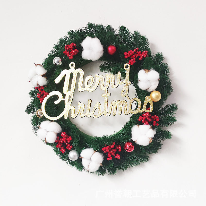 Christmas wreath with green pine, white cotton, red berries, ornaments, and gold Merry Christmas sign