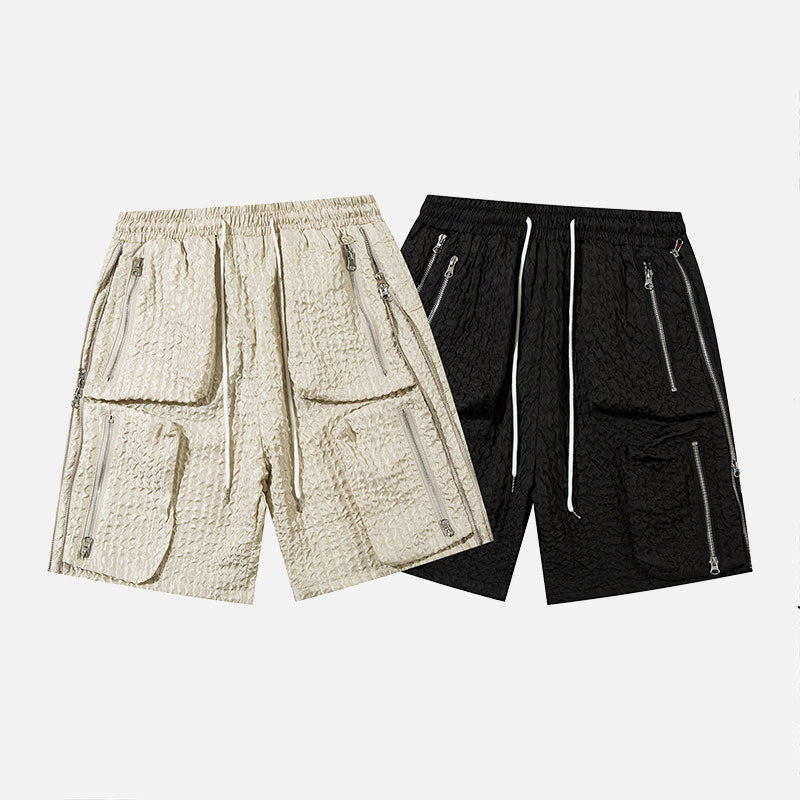 Pair of men's loose workwear shorts in beige and black polyester cotton blend with zippered pockets