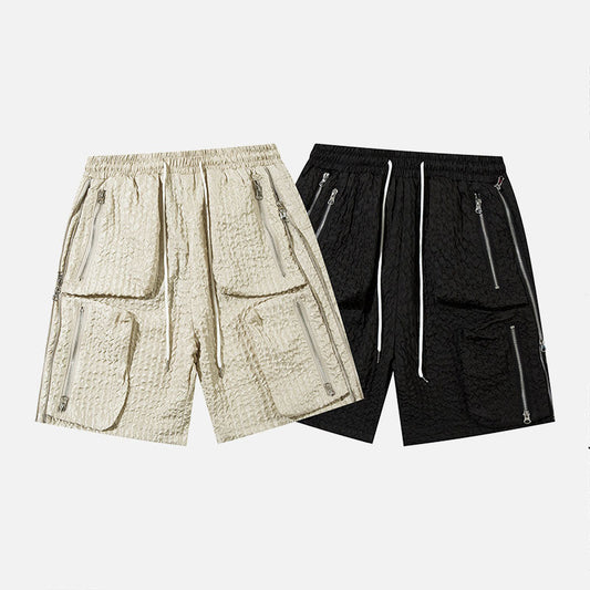 Pair of men's loose workwear shorts in beige and black polyester cotton blend with zippered pockets