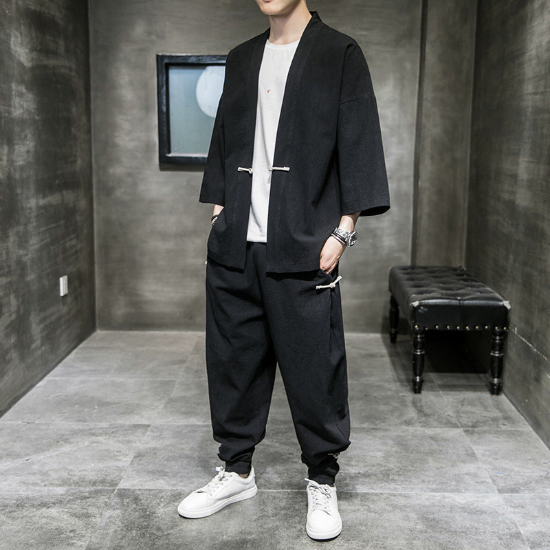 man wearing black loose-fit linen hanfu suit with white sneakers in minimalist gray room