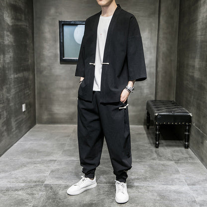 man wearing black loose-fit linen hanfu suit with white sneakers in minimalist gray room
