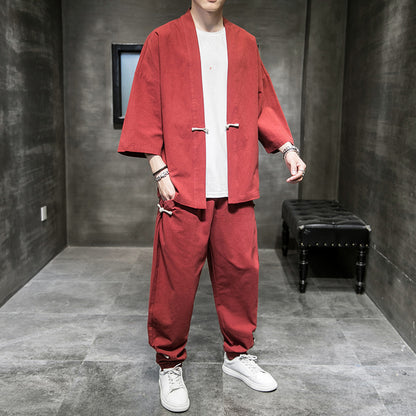 Man wearing loose-fit red linen hanfu suit with white sneakers in minimalist gray room