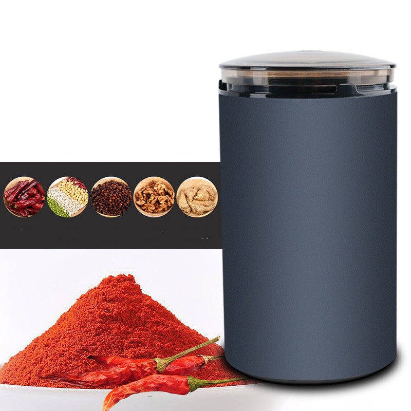Navy blue electric herb grinder with clear lid next to ground red chili powder and whole chili peppers