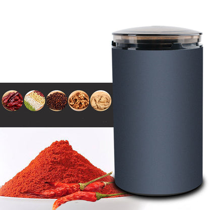 Navy blue electric herb grinder with clear lid next to ground red chili powder and whole chili peppers