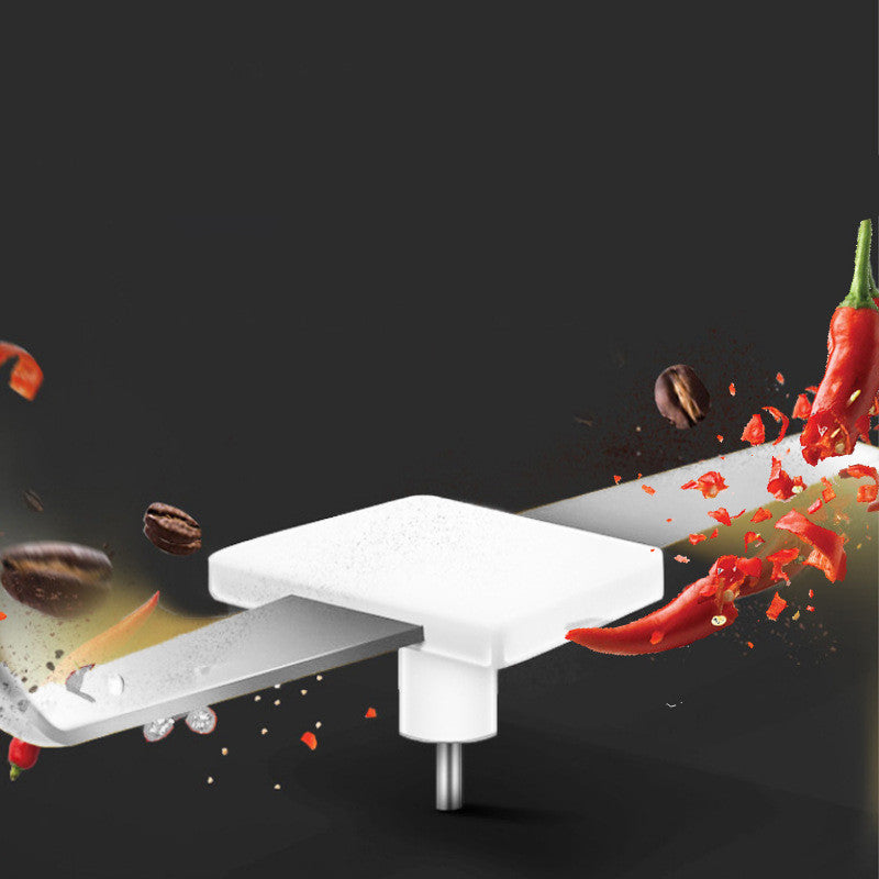 Electric herb grinder silver blade chopping red chili peppers and coffee beans on black background