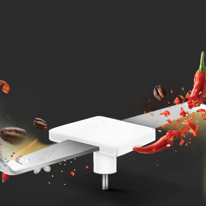 Electric herb grinder silver blade chopping red chili peppers and coffee beans on black background