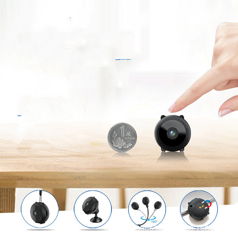 Mini black wireless security camera next to a 1 yuan coin on a wooden table with hand touching camera