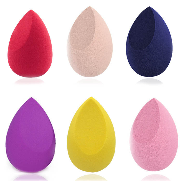 Set of six colorful makeup sponges in red, beige, navy, purple, yellow, and pink on white background