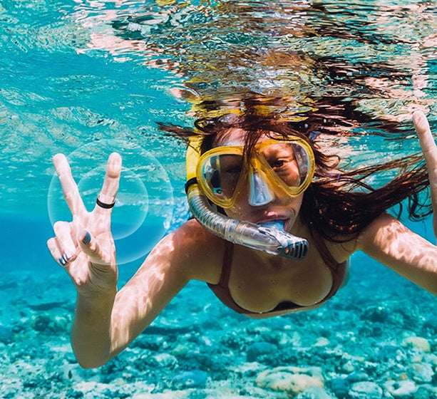 Woman snorkeling underwater wearing yellow mask and Trendoligy smart Bluetooth ring on finger