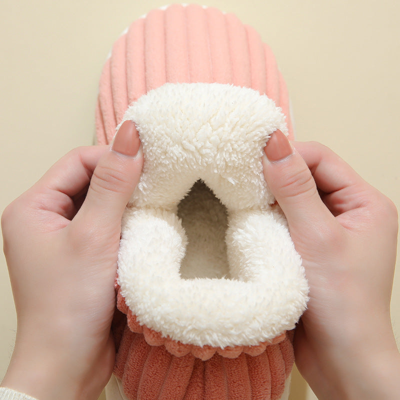 Hands holding a soft pink plush slipper with white fluffy interior, cozy indoor footwear