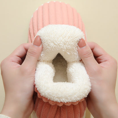 Hands holding a soft pink plush slipper with white fluffy interior, cozy indoor footwear