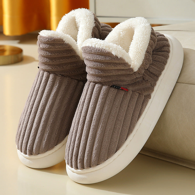 Brown ribbed plush slippers with white fleece lining and white soles on beige surface